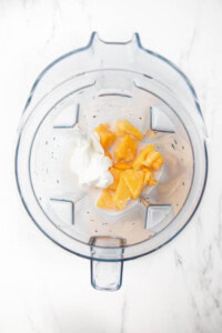 Ingredients for mango pineapple smoothie in a blender