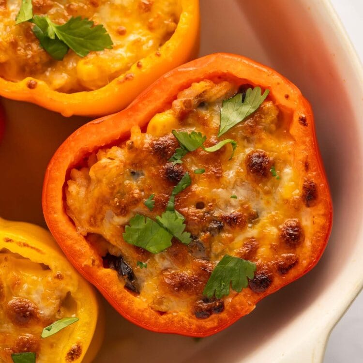 Mexican stuffed peppers with ground turkey and melted cheese in a casserole dish.