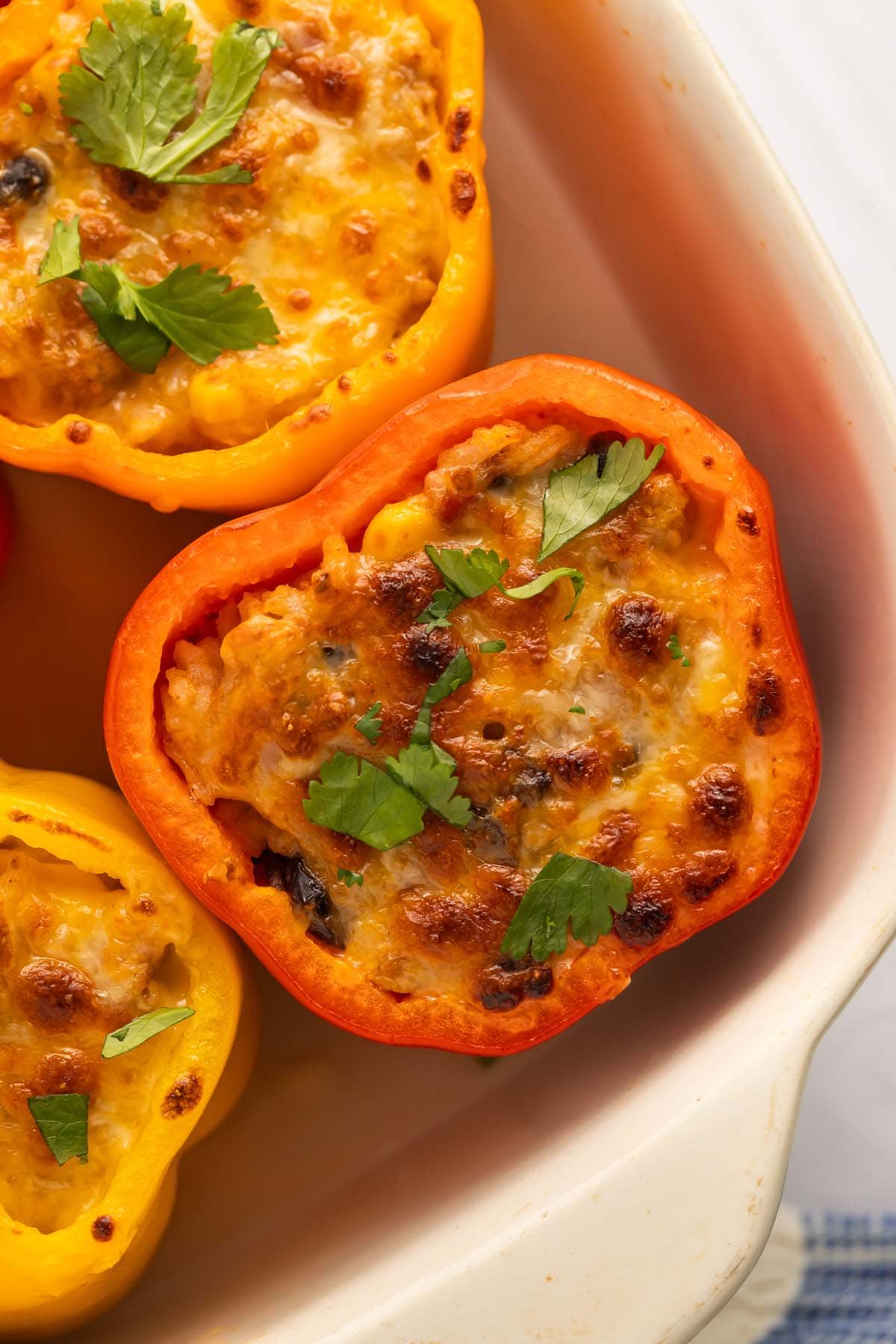 Mexican stuffed peppers with ground turkey and melted cheese in a casserole dish.