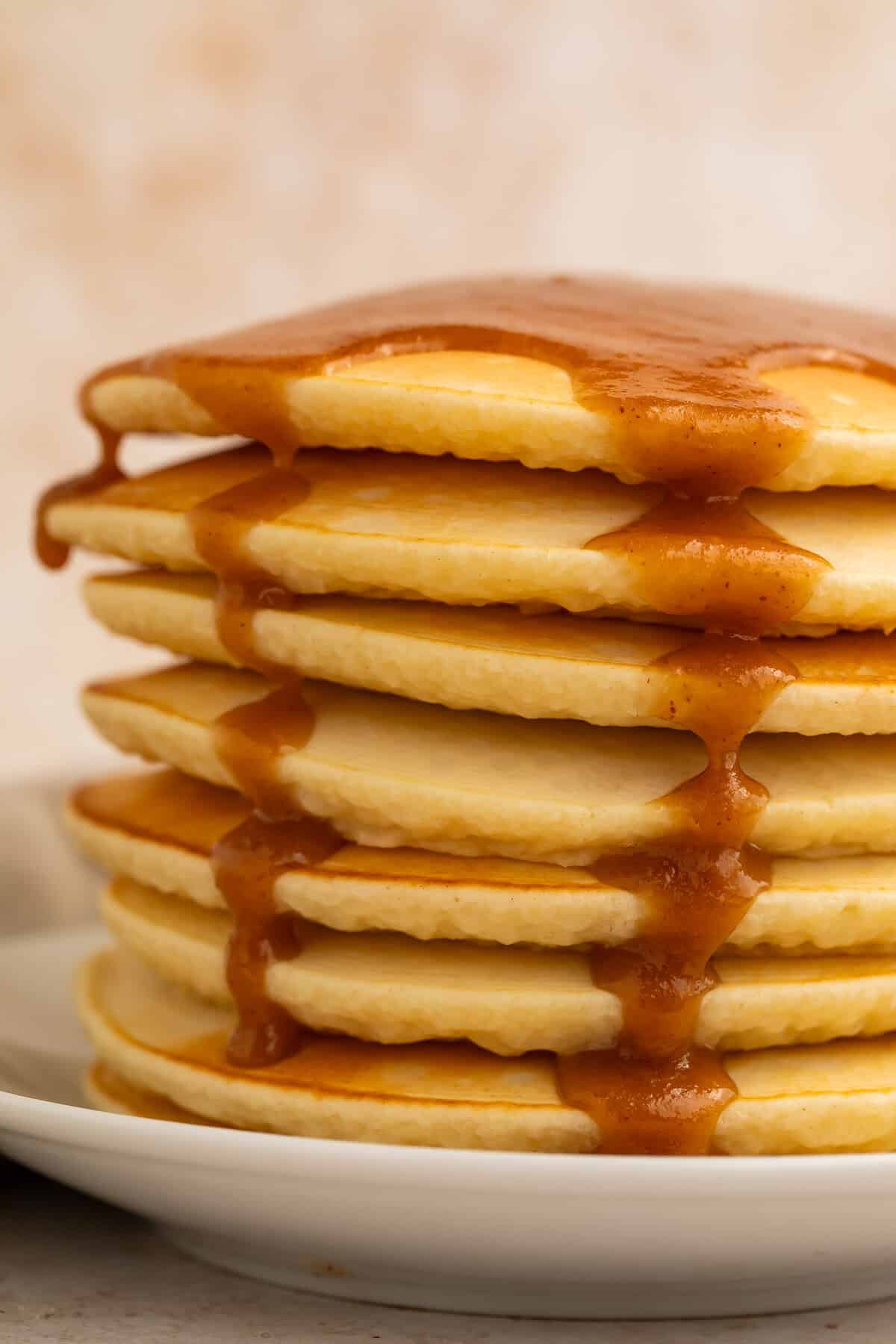 Stack of pancakes topped with peanut butter maple syrup running down the sides.
