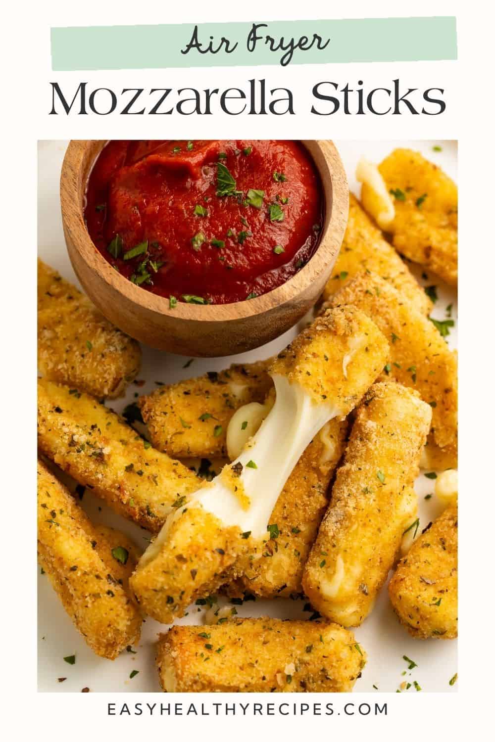 Close up of a plate of mozzarella sauce with a wooden bowl of tomato sauce for dipping. One of the mozzarella sticks is broken in half to show the cheese pull, and there is Pinterest-optimised text overlay.