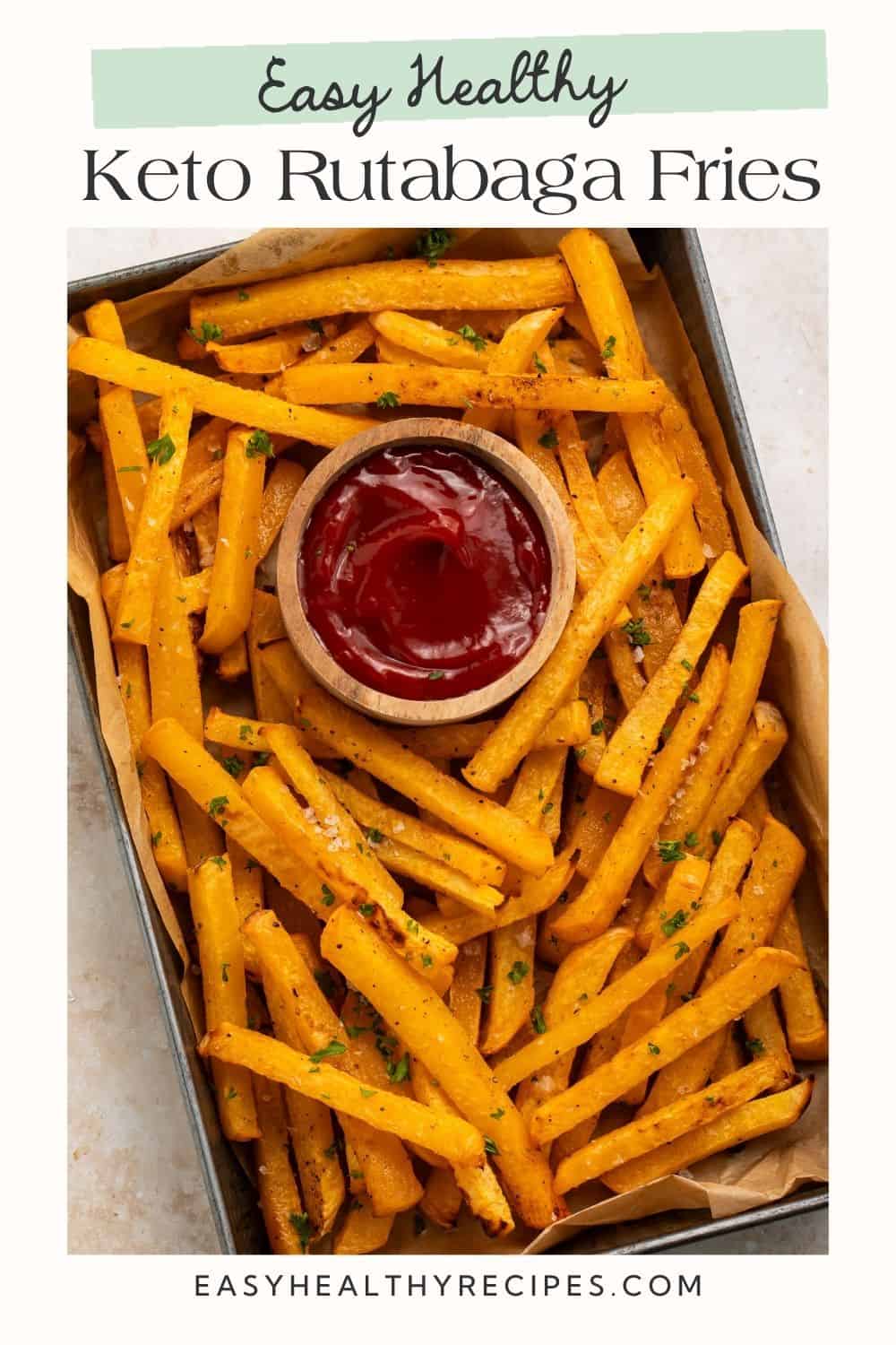 Baking tray of rutabaga fries with a pot of tomato ketchup. There is a white frame on the image with a Pinterest-optimised text overlay.