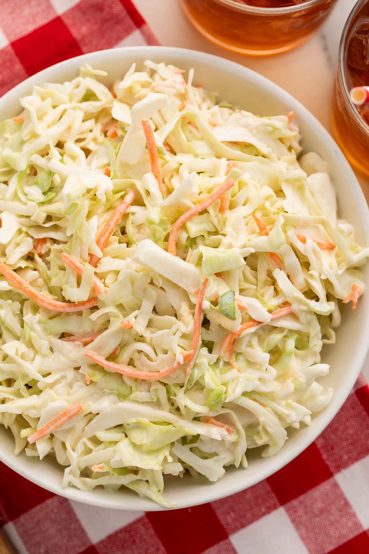 A large bowl of copycat Chick-fil-a coleslaw on a red and white checkerboard tablecloth.