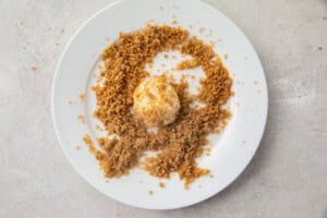 Cream cheese fat bomb rolled in a snickerdoodle crumble on a white plate