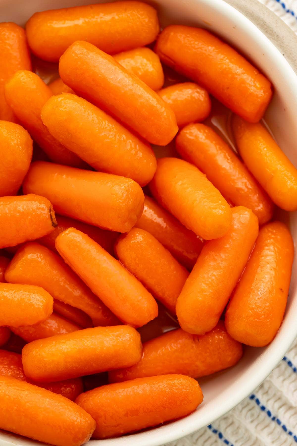 A white bowl holding buttery carrots cooked in the Instant Pot.