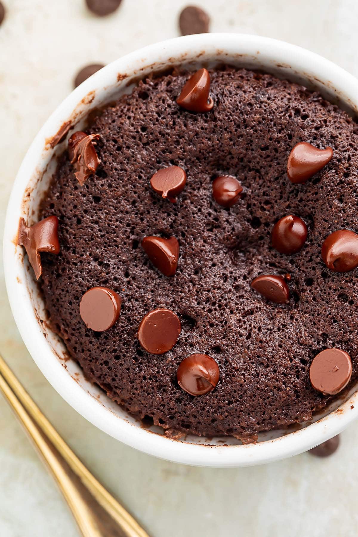 Close-up on a keto mug brownie topped with keto chocolate chips in a white coffee mug.