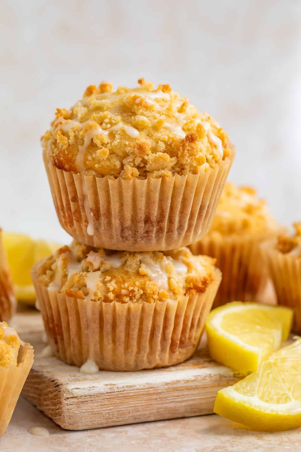 A pair of lemon muffins stacked on top of each other on a serving board with lemon wedges.