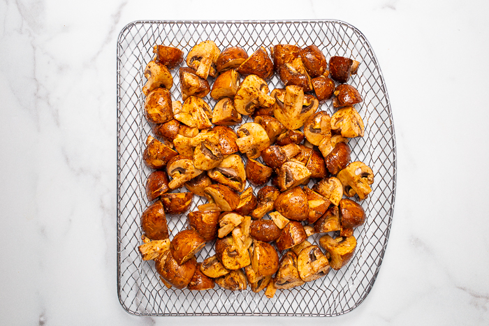 Marinated mushrooms resting on a air fryer tray