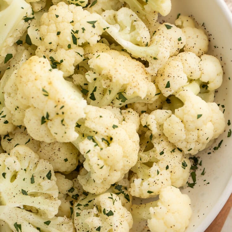 Close-up of a large white bowl holding tender florets of Instant Pot Cauliflower.