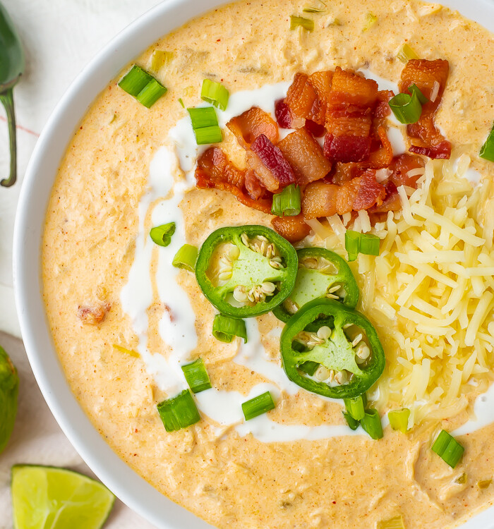 A bowl of keto white chicken chili topped with jalapeno slices and bacon