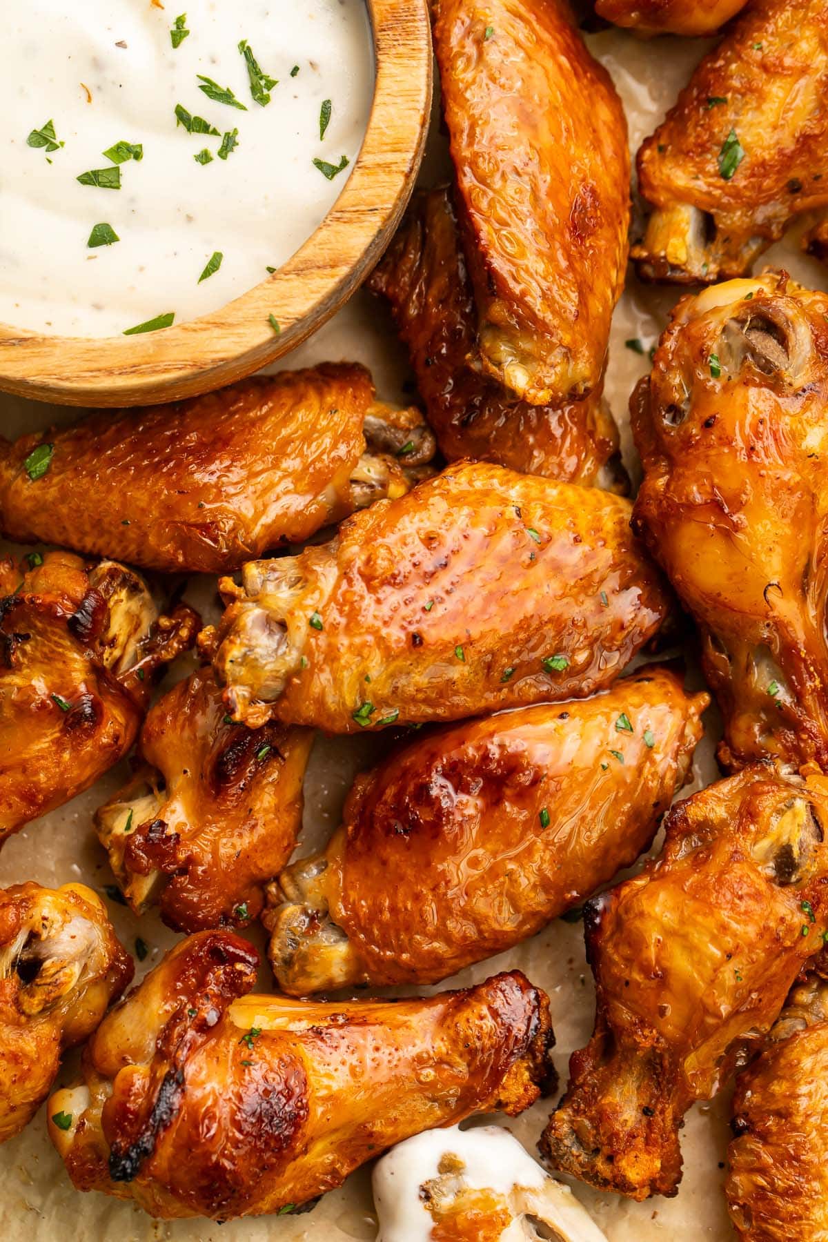 A spread of brined chicken wings on a sheet pan with a small dipping bowl of ranch dressing.
