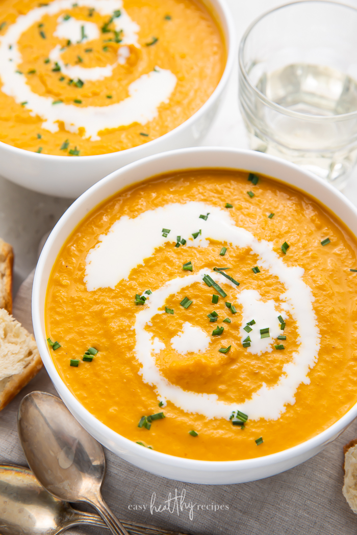 Overhead shot of two bowls of pumpkin bisque garnished with cream and chives