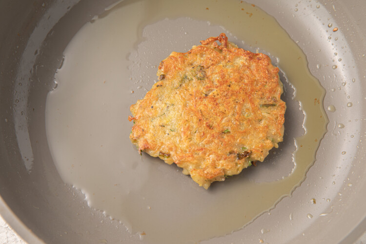 Fried vegan latke in a grey nonstick pan