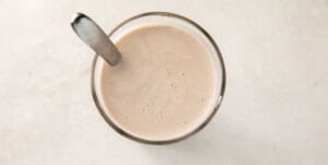 Glass of keto chocolate milk with a silver spoon