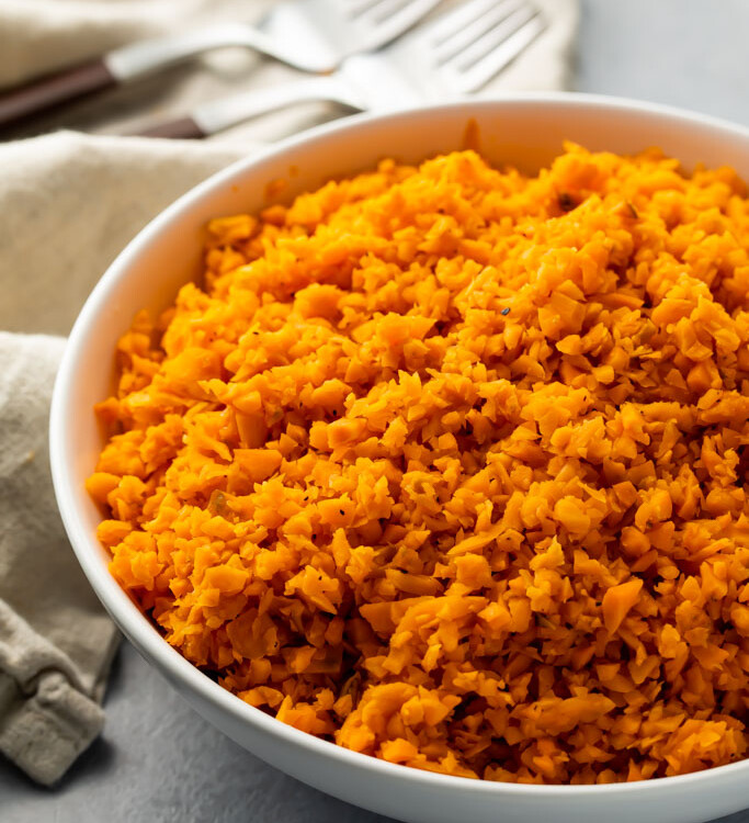 White bowl of bright orange sweet potato rice