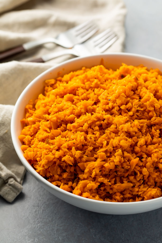 White bowl of bright orange sweet potato rice