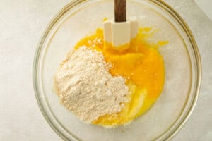 Ingredients for keto dumpling dough mixture in a glass bowl with a rubber spatula