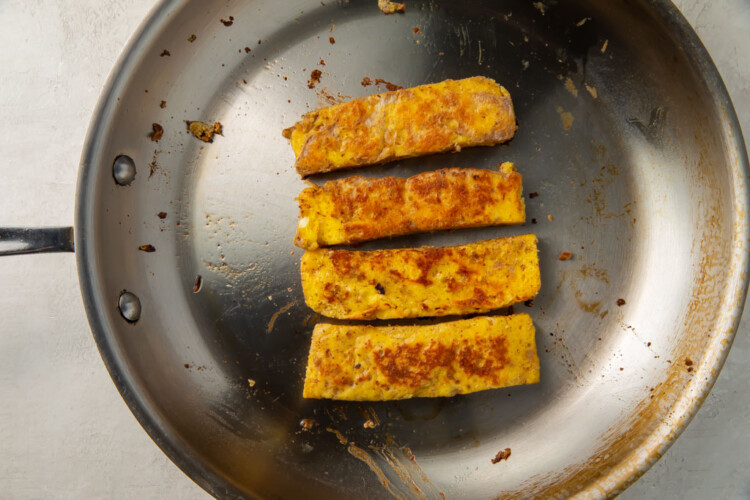 Four fried toast sticks in a medium-sized silver skillet