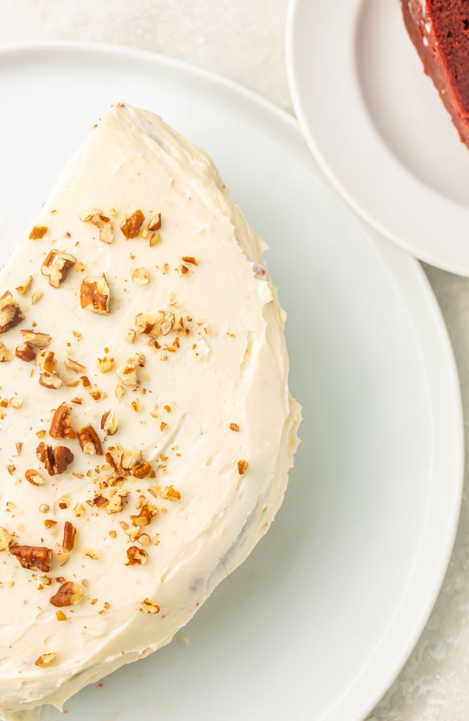 Overhead view of keto red velvet cake topped with chopped pecans and cream cheese frosting