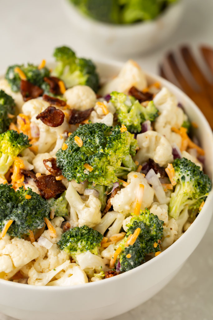 Close up photo of a white bowl of Amish broccoli salad, taken from the side