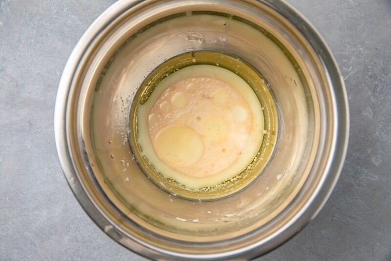Wet ingredients for gluten-free mug cake in a large silver mixing bowl.