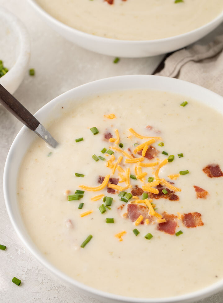 Angled photo of Irish potato soup topped with bacon, cheddar, and chives
