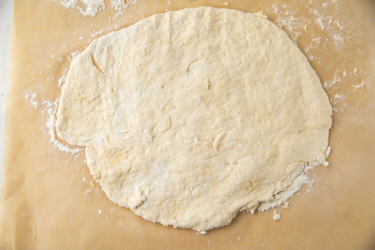 Flattened biscuit dough on parchment paper