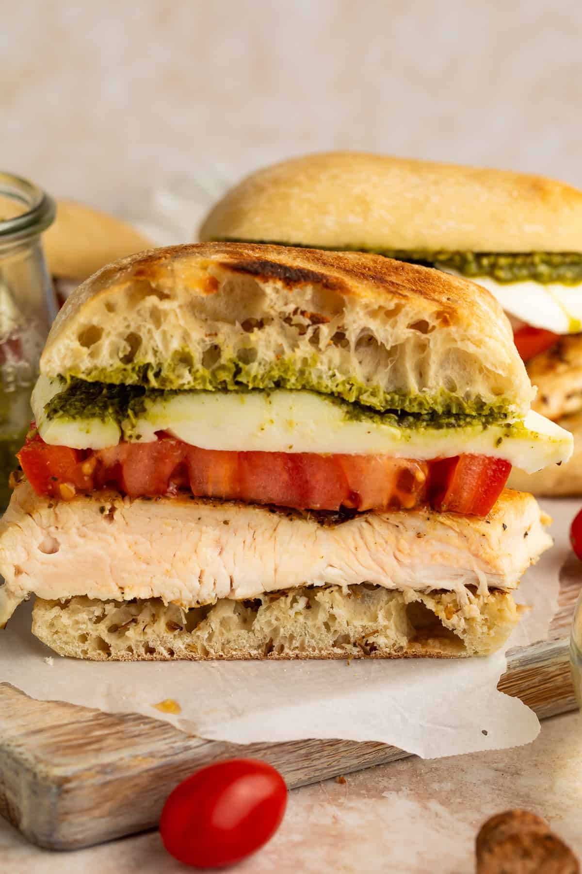 Close up of a chicken, mozzarella, tomato and pesto toasted sandwich cut crossways to show the fillings.