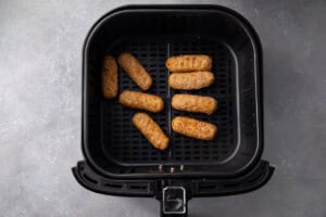 Frozen mozzarella sticks in an air fryer basket