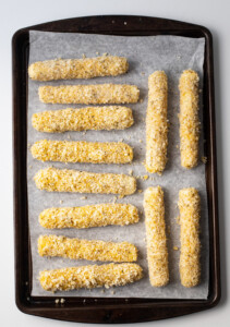 Gluten free mozzarella sticks on a baking sheet lined with parchment paper