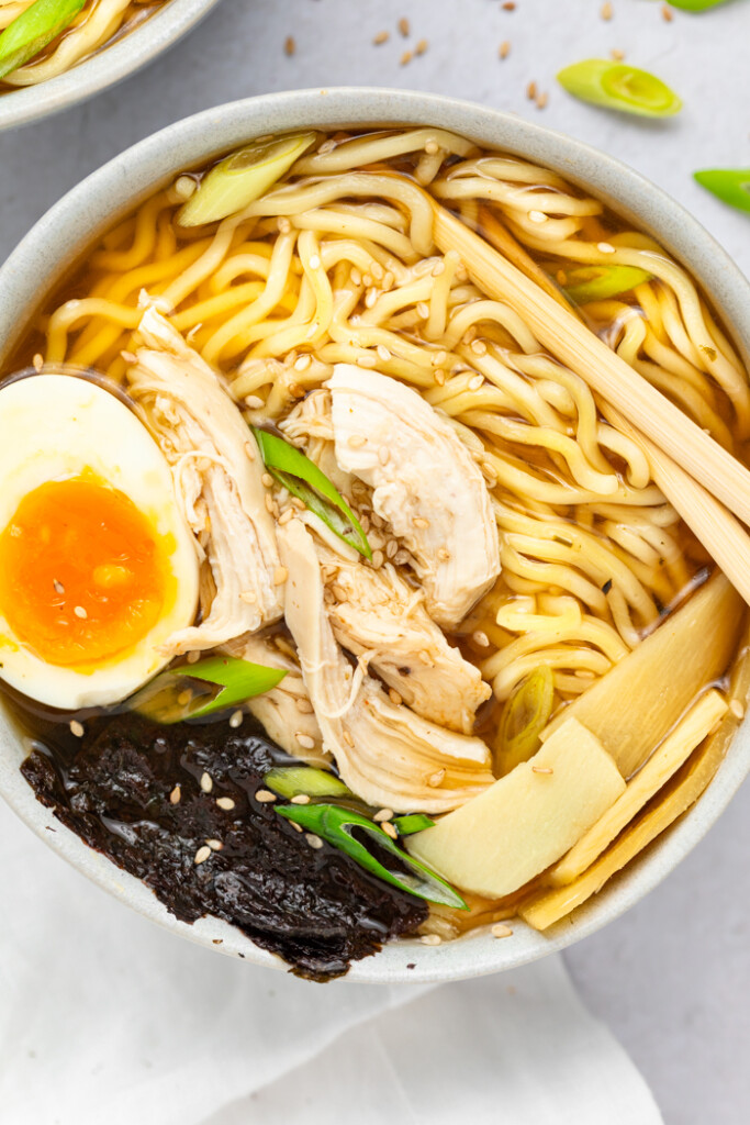 Spicy Chicken Ramen in a bowl topped with a soft boiled egg, scallions, and sesame seeds.