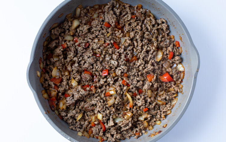 Ground beef with onion, beef broth, bell pepper, and spices in skillet
