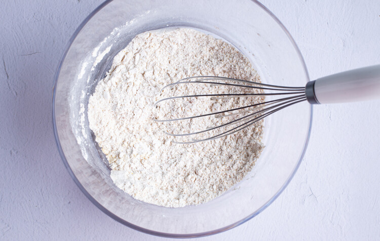 Dry ingredients for gluten free onion ring batter in a large glass mixing bowl with a whisk