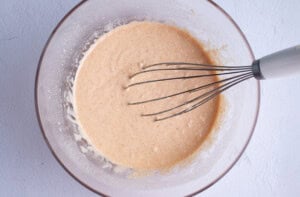 Gluten free onion ring batter in large glass mixing bowl with whisk