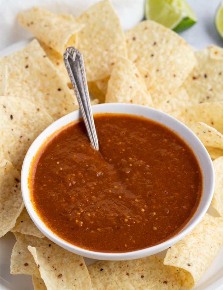 Tomatillo red chili salsa in a white bowl surrounded by tortilla chips