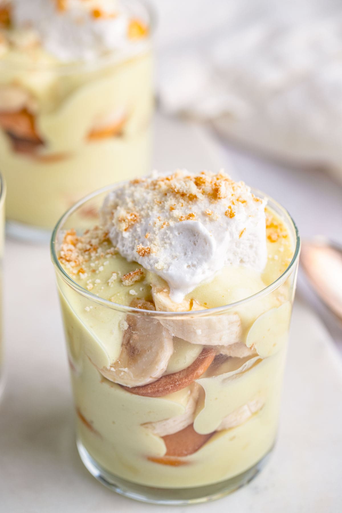 Angled view of a small glass of vegan banana pudding with banana slices and Nilla wafers.