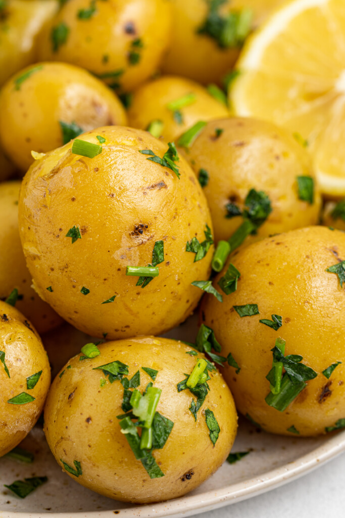 close up image of steam potatoes on a plate with a lemon
