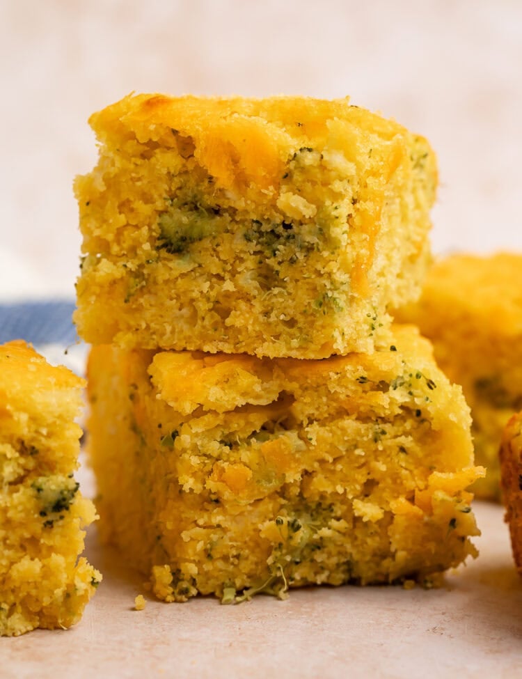 Two squares of broccoli cornbread, stacked one on top of the other.