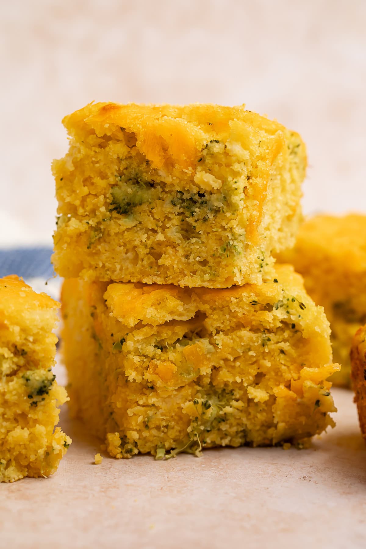 Two squares of broccoli cornbread, stacked one on top of the other.
