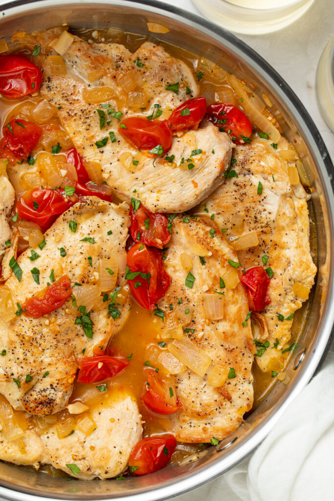overhead image of chicken pomodoro in a skillet with white wine on the side