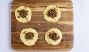 Unfolded empanadas on a wooden cutting board