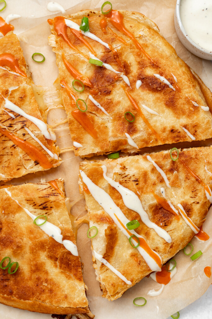 overhead image of buffalo chicken quesadillas with ranch dressing and buffalo sauce drizzled on top