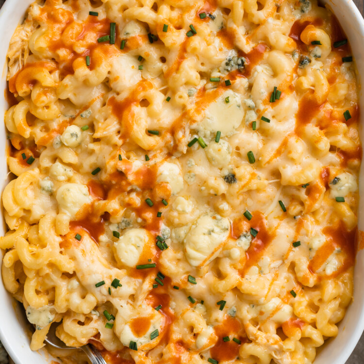 Close up, overhead view of buffalo chicken mac and cheese in a casserole dish on a dark wooden background.