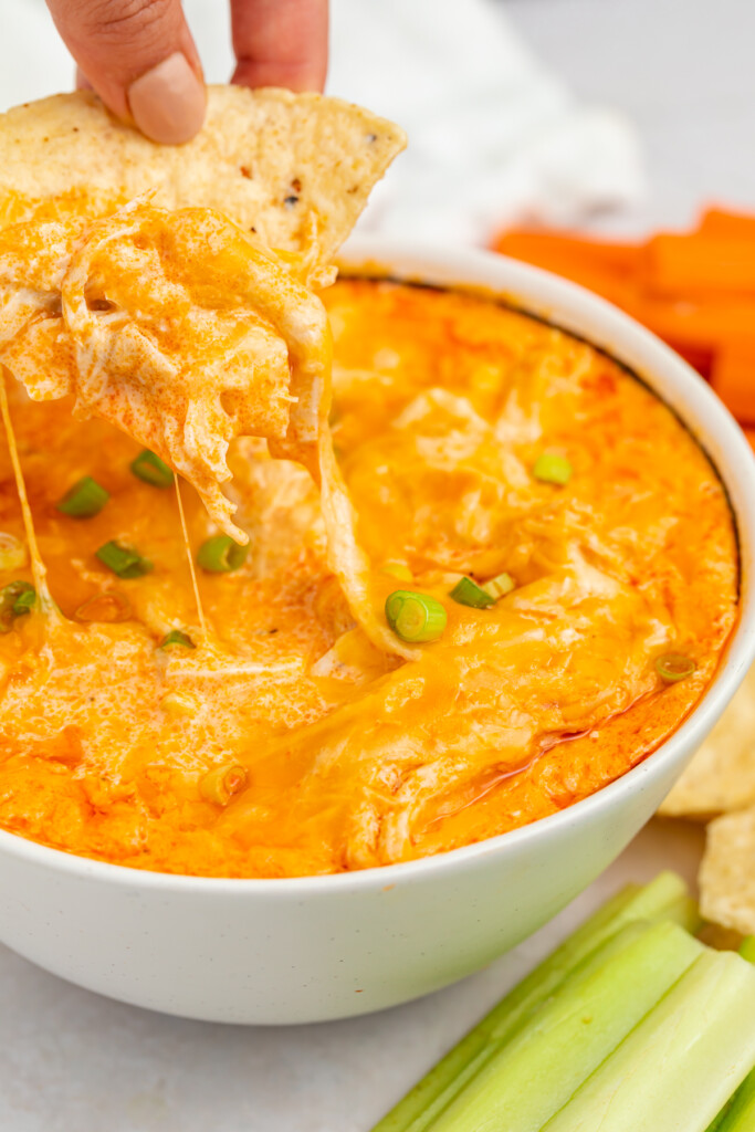 a chip being dipped into a bowl of instant pot buffalo chicken dip