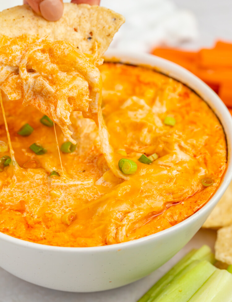 a chip being dipped into a bowl of instant pot buffalo chicken dip
