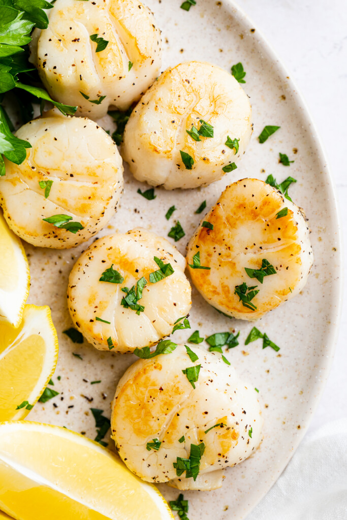 overhead image of air fryer scallops on a plate with fresh parsley on top