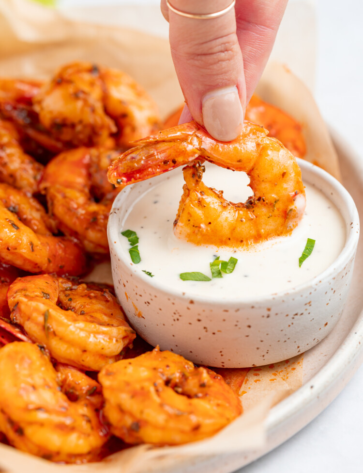 buffalo shrimp being dipped into a bowl of ranch dressing