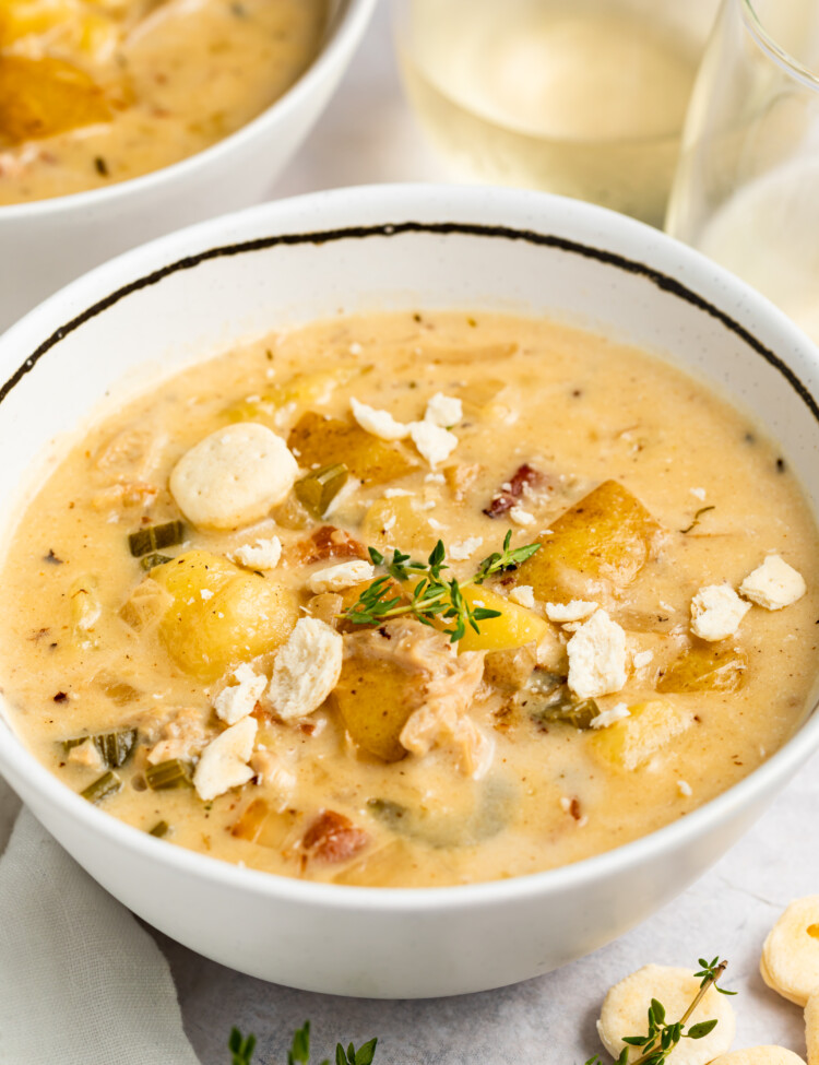 two bowls of instant pot clam chowder with white wine, crackers, and thyme on the side