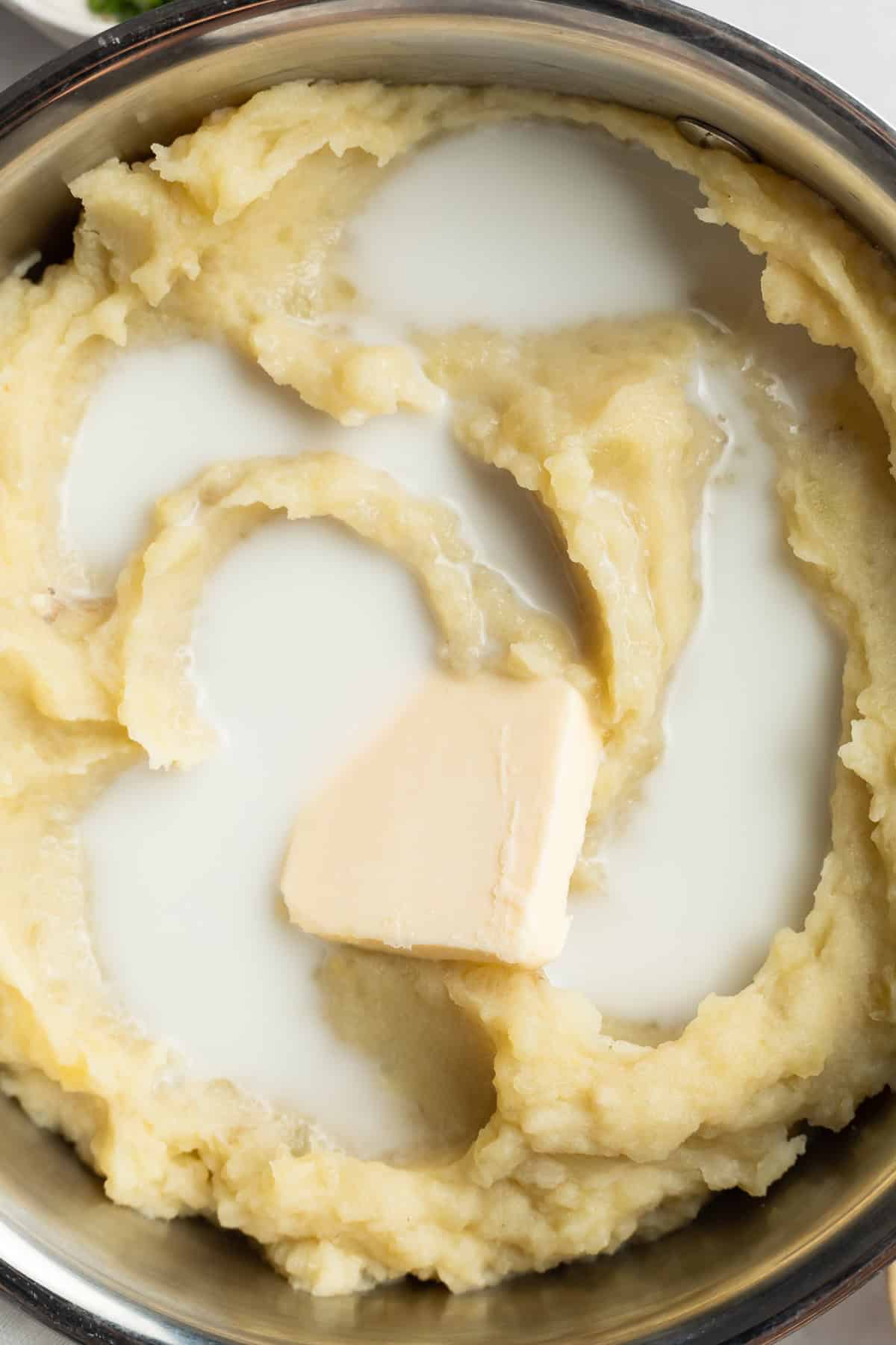 close-up image of mashed potatoes, milk, and butter in a pot