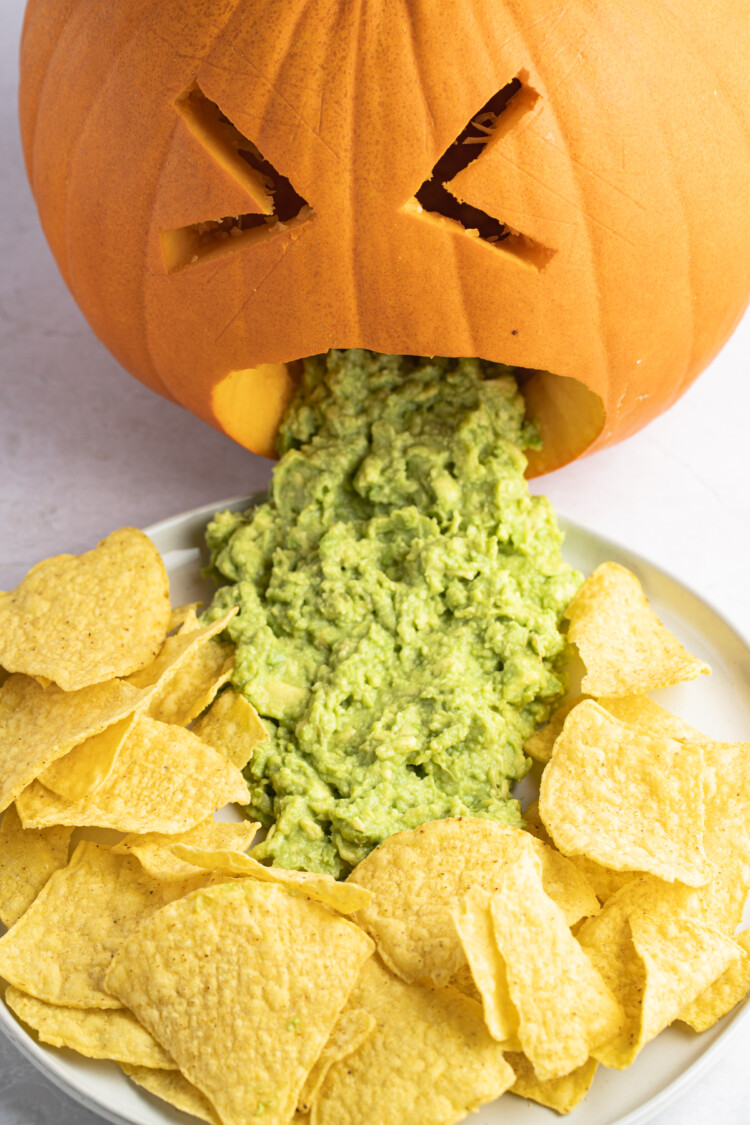 Close-up of a puking pumpkin with guacamole and tortilla chips